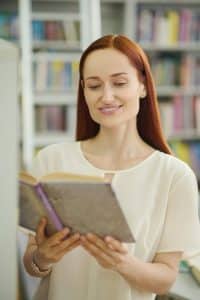 Dame leser bok i biblioteket