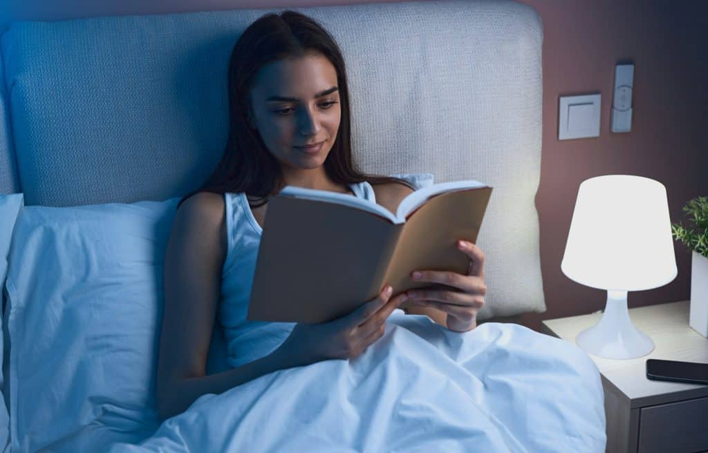 Dame leser bok i sengen